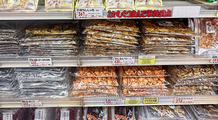 Scaffali pieni di snack confezionati e prodotti ittici essiccati all'interno di Niki no Kashi a Ueno, Tokyo.