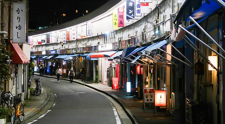 Strada curva a Noge, Yokohama, di notte con negozi e insegne luminose.