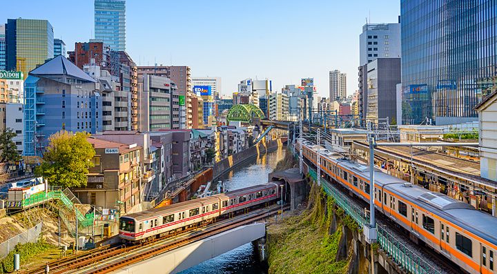 Treni attraversano il fiume Kanda a Ochanomizu, Tokyo con edifici moderni.