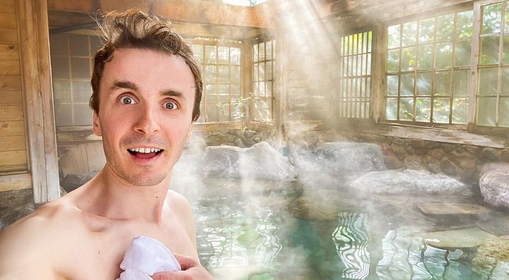 Marco Togni si scatta un selfie all'interno di un onsen a Yufuin, con vapore che avvolge la vasca in pietra.