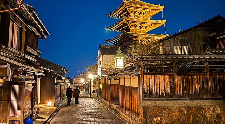 La pagoda Yasaka a Kyoto svetta illuminata durante una notte limpida sopra la strada acciottolata del quartiere storico.
