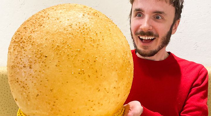 Marco Togni tiene in mano una gigantesca palla fritta al sesamo, un dolce servito al ristorante Mara Daigaku a Ueno.
