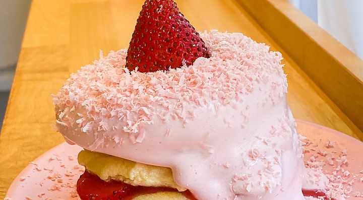 Un soffice pancake alla fragola con crema rosa e fragola fresca sopra un piatto rosa al Belle Epoque.