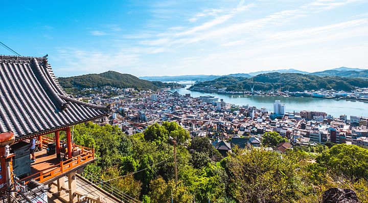 Vista panoramica di Onomichi dal tempio Senkoji con tetti tradizionali in primo piano e il mare sullo sfondo.