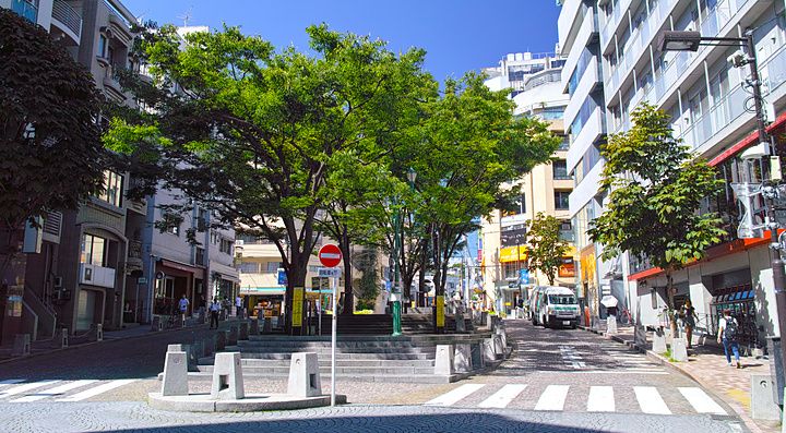 Veduta di Piazza Patio No. 10 ad Azabu-Juban, Tokyo, con alberi, edifici commerciali e una pavimentazione a motivi.