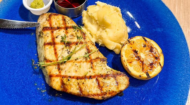 Un piatto con pollo a Sizzler grigliato, purè di patate e limone su un tavolo di legno nel ristorante Sizzler.