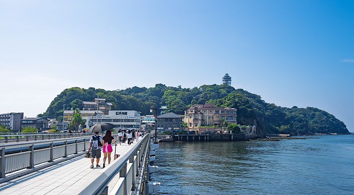 Persone che percorrono il ponte Enoshima Benten verso l'isola di Enoshima in una giornata di sole.