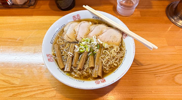 Una ciotola di ramen con maiale e bambù servita su un bancone di legno presso Midoriya Ramen a Hirosaki.