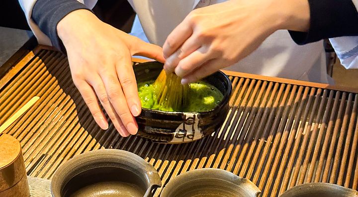 Un individuo prepara il tè matcha con un chasen in una ciotola di ceramica presso Sakurai Japanese Tea Experience a Tokyo.