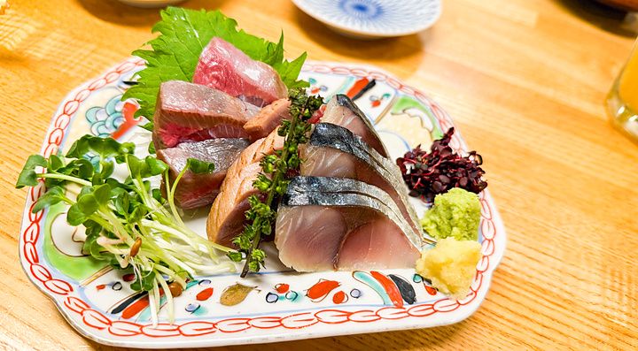 Sashimi assortito servito in un piatto decorato presso l'izakaya Hatonoyu a Tokyo.