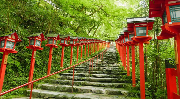 Scalinata in pietra che conduce al santuario di Kifune a Kyoto, fiancheggiata da caratteristiche lanterne rosse.