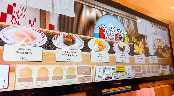 Uno schermo per ordinare a Sushiro con immagini di piatti di sushi e dessert selezionabili tramite interfaccia touch.