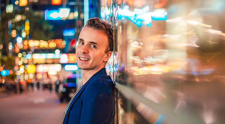 Marco Togni appoggiato a un muro illuminato dai neon a Ginza.