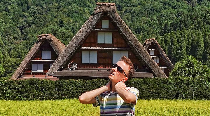 Persona in un campo di riso con case Gassho-zukuri sullo sfondo a Shirakawa-go.