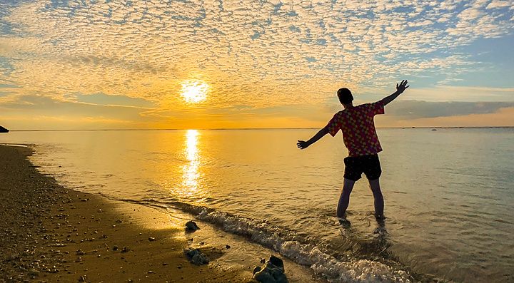 persona al tramonto sulla spiaggia Mimikiri con cielo nuvoloso.