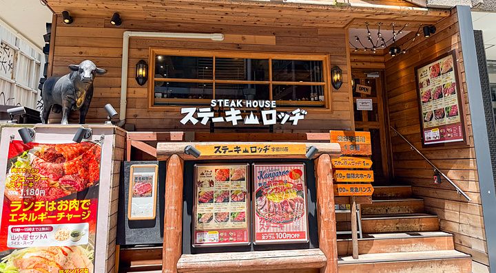 La facciata in legno del Ristorante Steak Lodge (Udagawacho), Shibuya, Tokyo, con insegne di menu e una statua di un toro.