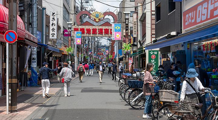 Veduta prospettica della strada commerciale Sugamo Jizodori a Tokyo con pedoni e biciclette parcheggiate.