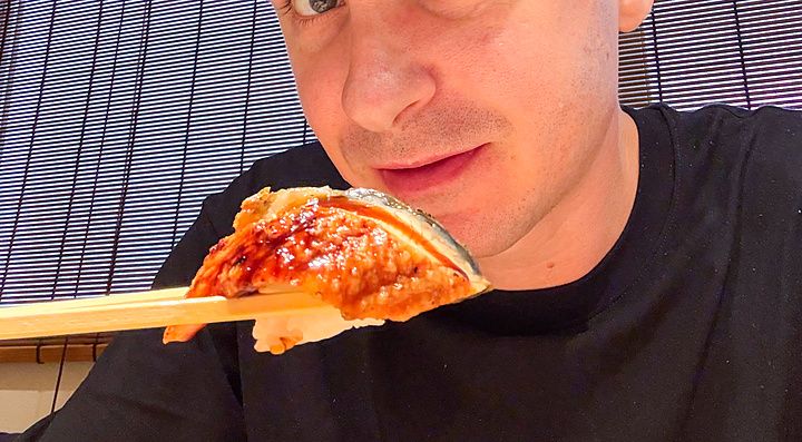 Marco Togni tiene in mano un pezzo di sushi con le bacchette all'interno del Ristorante New Sushi Center Harukiya a Osaka.