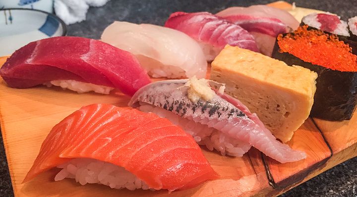 Un assortimento di nigiri e gunkan sushi servito su un tagliere di legno al ristorante Sushidokoro Okame a Tokyo.