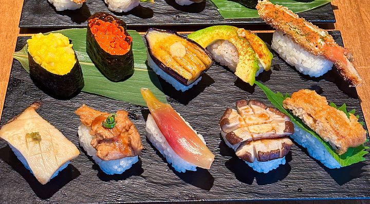 Assortimento di nigiri vegani serviti su piatti di ardesia nera presso il ristorante Vegan Sushi Tokyo a Shibuya.
