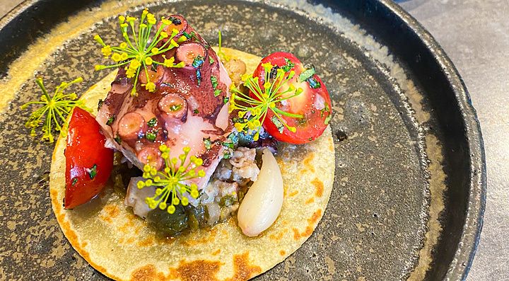 Taco morbido con polpo, pomodorini e capperi, servito accanto a un secondo di carne al ristorante Ode di Tokyo.