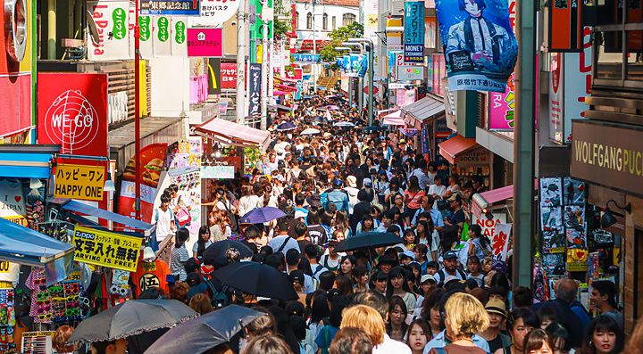 Strada affollata a Takeshita Dori con negozi e cartelli colorati.