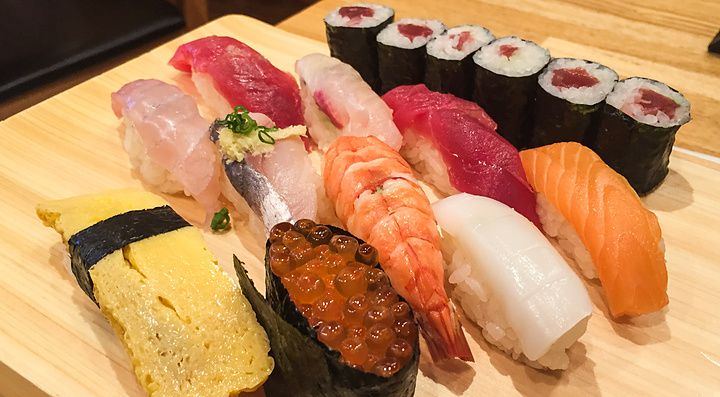 Una varietà di nigiri e hosomaki disposti su un tagliere di legno al Tama Sushi a Tachikawa.