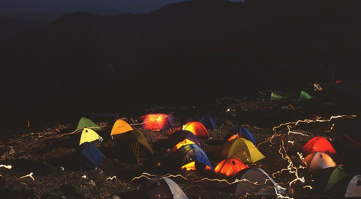 Tende colorate illuminate di notte con il monte Fuji sullo sfondo.