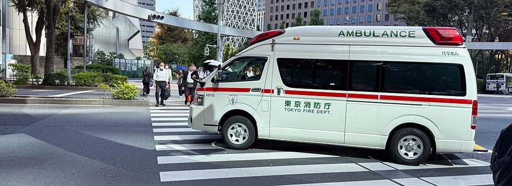 Ambulanza attraversa un incrocio a Shinjuku, Tokyo, tra grattacieli moderni.
