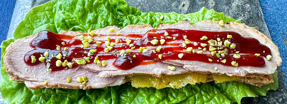 Anatra laccata a fette con salsa a China Blue a Tokyo servita su una foglia di lattuga e una base di pietra scura.