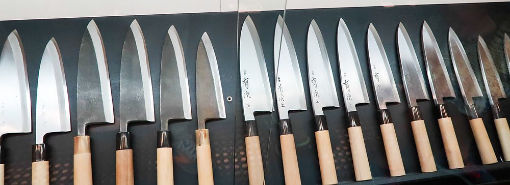 coltelli esposti in una vetrina ad aritsugu, kyoto, con manici in legno.