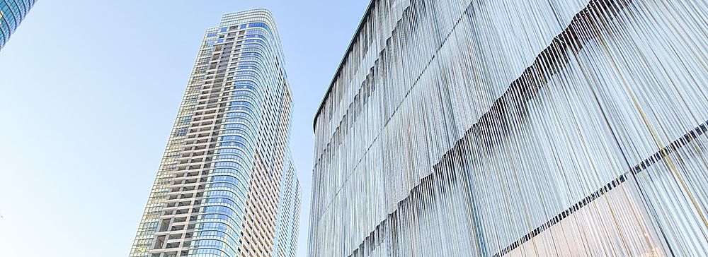 Boutique di lusso con facciata a fili metallici presso Azabudai Hills a Tokyo, con grattacieli sullo sfondo.