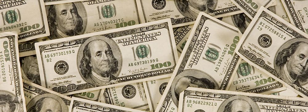 Pila di banconote da 100 dollari americani disposte casualmente.