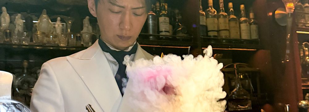 Un barista in divisa bianca prepara un cocktail fumante dietro il bancone del Bar Centifolia a Tokyo.