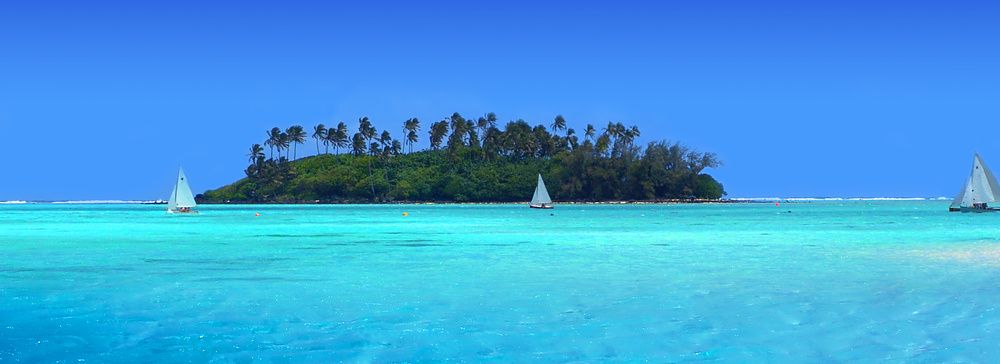 Barche a vela vicino a un'isola tropicale con acque turchesi.