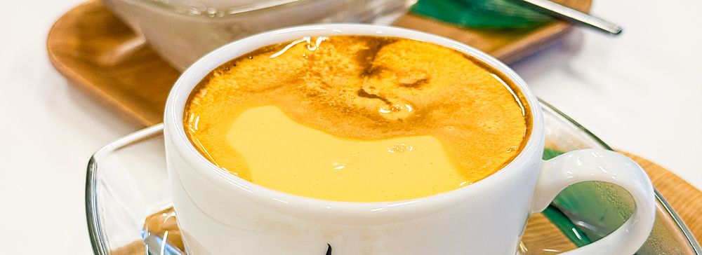 Due tazze di caffè all'uovo con il logo del Café Giang posate su vassoi di legno a Yokohama.