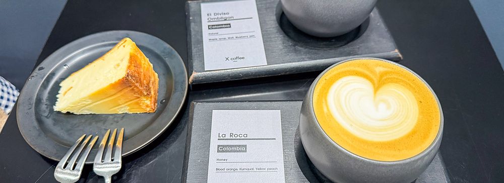 Due tazze di caffè con latte art e una fetta di dolce su un tavolo nero presso X coffee a Ginza, Tokyo.