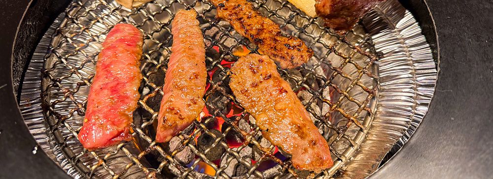 Tagli di carne e funghi che cuociono su una griglia circolare all'interno del Ristorante Toraji.