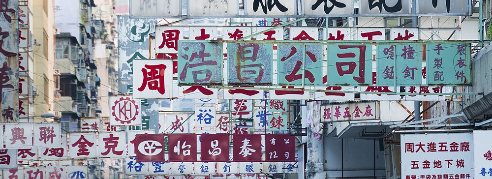 Cartelloni pubblicitari su una strada affollata a Hong Kong con scritte in cinese.