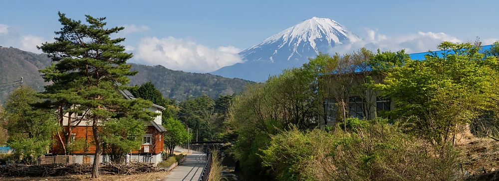 Casa tradizionale giapponese vicino a un canale con vista sul monte Fuji innevato in una giornata di primavera.