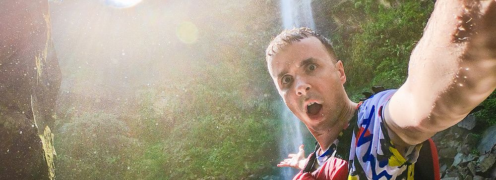 Marco Togni con giubbotto di salvataggio rosso scatta un selfie davanti alle Cascate di Pinaisara sull'Isola Iriomote.