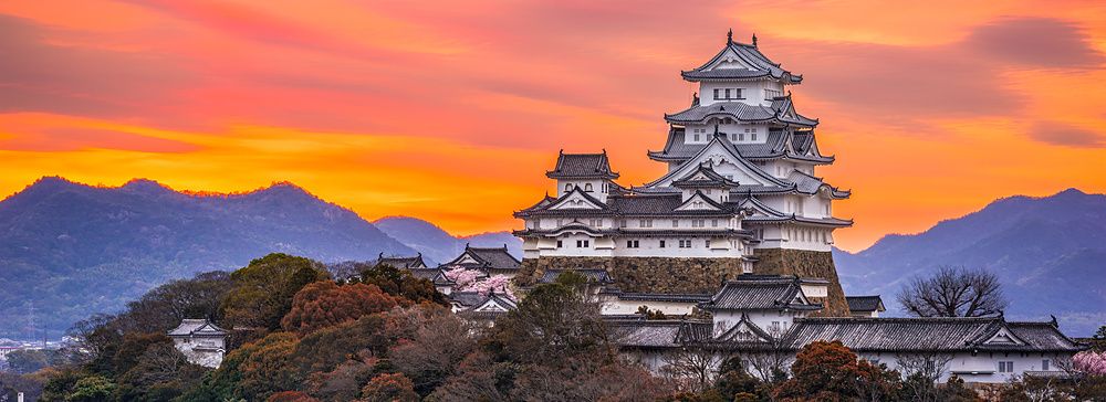 Castello di Himeji in Giappone all'alba con un cielo arancione e rosa.
