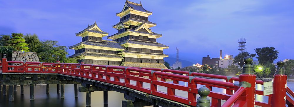 Castello di Matsumoto al crepuscolo con ponte rosso e cielo blu.