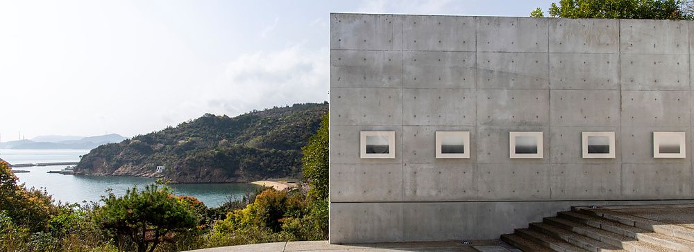 Parete in cemento a vista con quadri incassati su un piazzale che affaccia sul Mare interno di Seto, in Giappone.