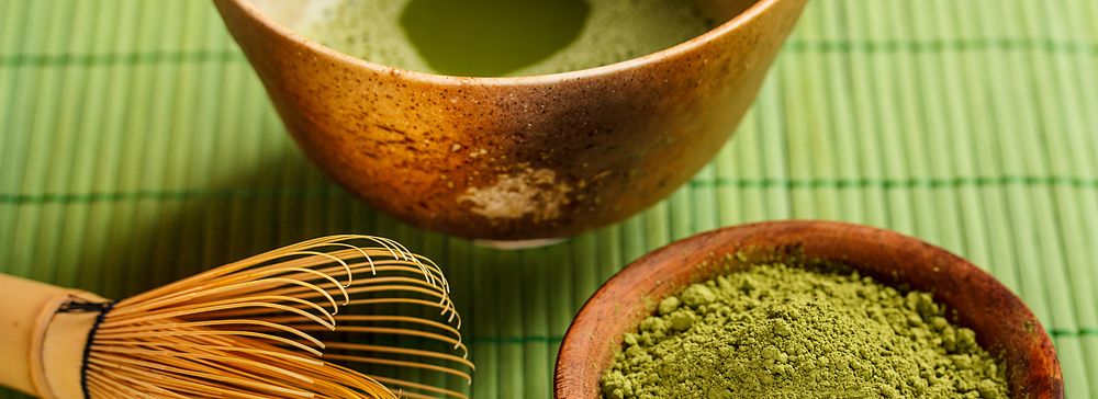 Ciotola di matcha e strumenti per la cerimonia del tè giapponese su tovaglietta verde.