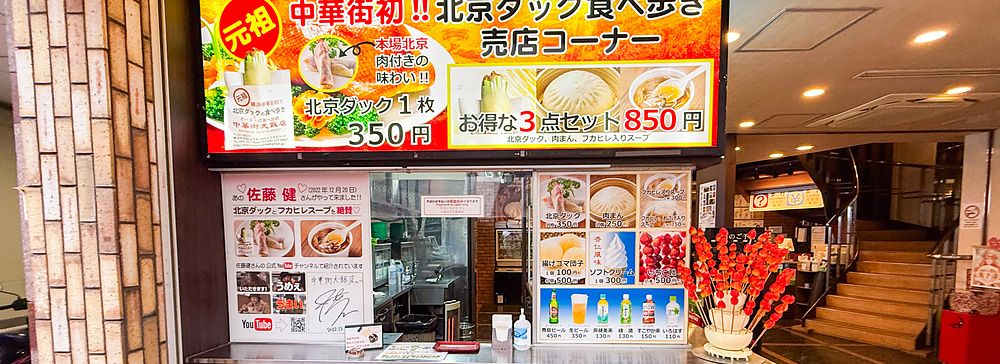 Esterno di Chukagai Daihanten con vetrina e cartellonistica per il cibo d'asporto nella Chinatown di Yokohama.