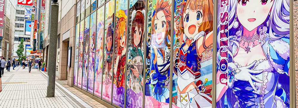 Strada di Akihabara con poster anime su parete di vetro.