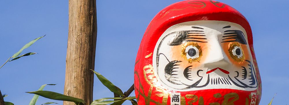 Due bambole Daruma rosse fissate su pali di legno durante il rituale del Dondoyaki in Giappone.