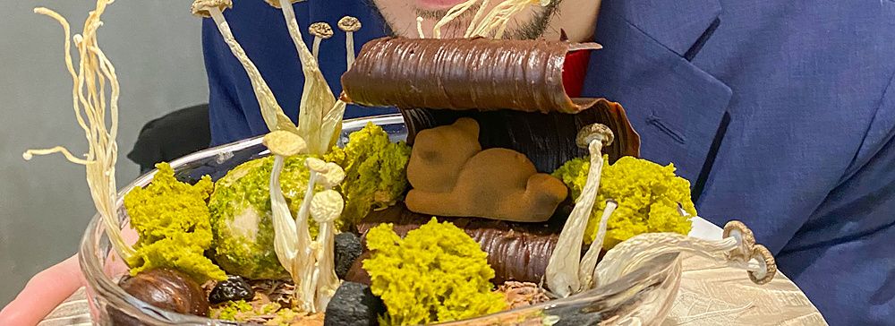 Marco Togni con occhiali rosa guarda un dolce con funghi servito in un piatto di vetro presso Le Musée a Ginza.