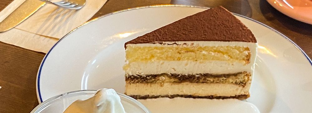 Una fetta di tiramisù, un gelato soft e un contenitore con caffè su un tavolo presso Takao Coffee.